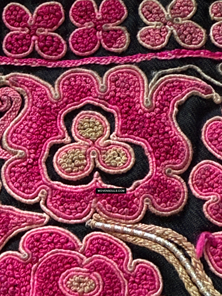 Close-up of old pink floral embroidery from Chinese minority community on black fabric