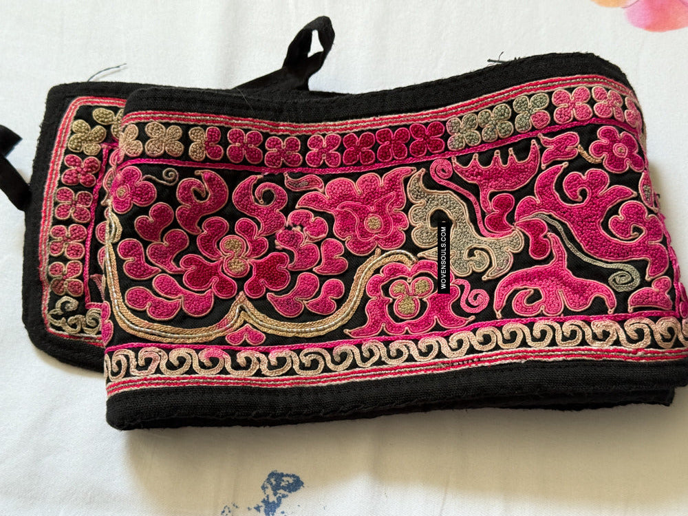 Black pouch with pink and gold embroidery on a white background