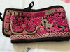 Black pouch with pink and gold embroidery on a white background
